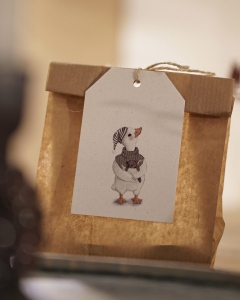 Świąteczny prezent ozdobiony papierową zawieszką Hi Little z ilustracją