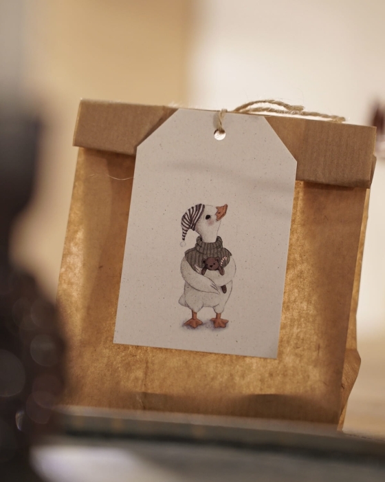 Świąteczny prezent ozdobiony papierową zawieszką Hi Little z ilustracją