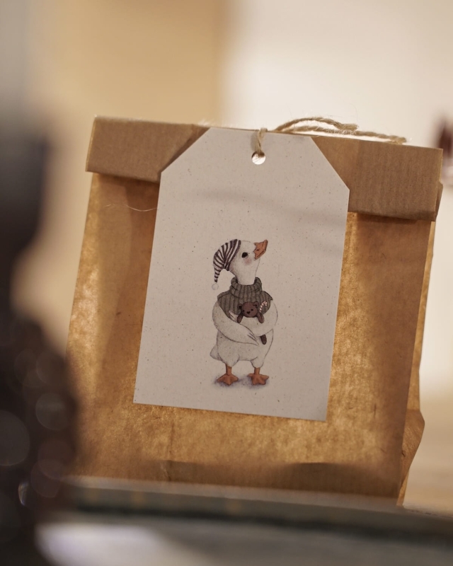 Świąteczny prezent ozdobiony papierową zawieszką Hi Little z ilustracją