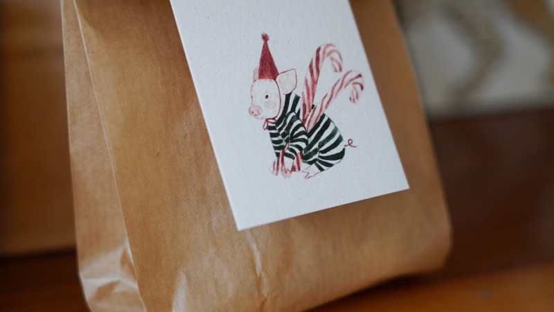Papierowa zawieszka do prezentu świątecznego Hi Little z ilustracją świnki na ozdobnie zapakowanym prezencie
